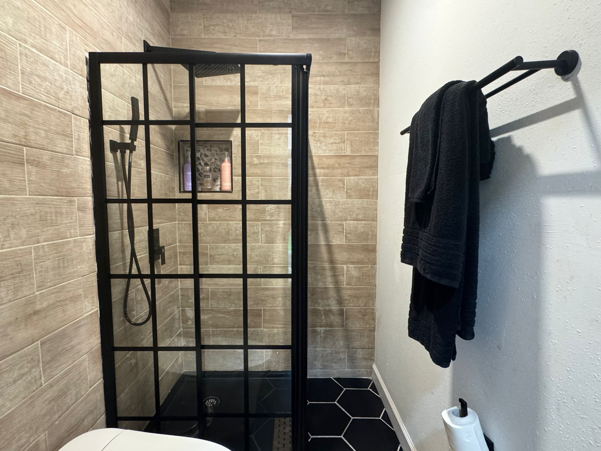 Un baño moderno con ducha de vidrio, inodoro y perchero para toallas.