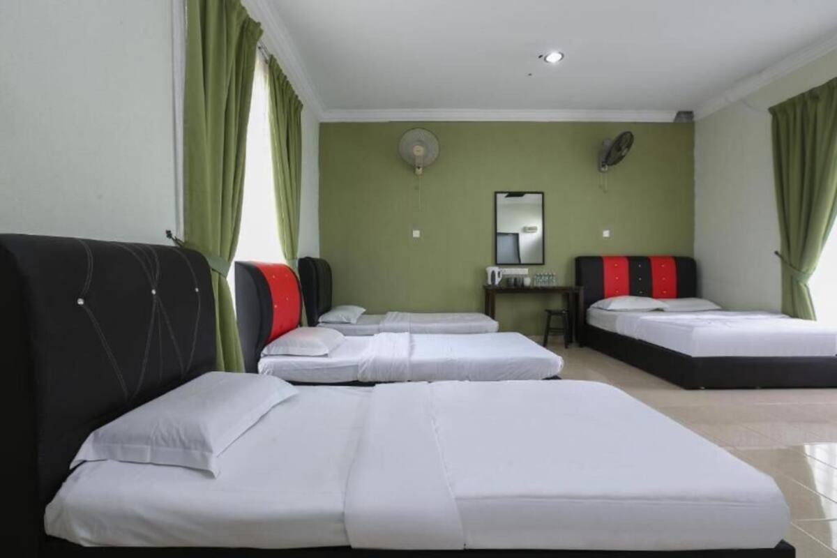 A hotel room with two beds, a desk, a mirror, and a fan.