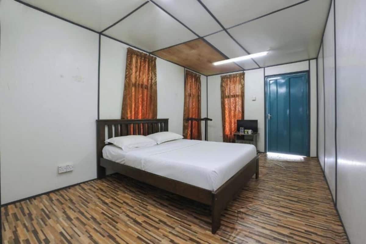 A bedroom with a wooden bed, a nightstand, a blue door, and patterned flooring.