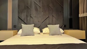 Une chambre d’hôtel avec un grand lit, deux oreillers à carreaux, une tête de lit sombre et une pancarte « Limonotto Suit Otel » posée sur le couvre-lit.