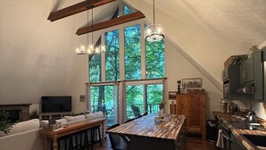 A spacious kitchen with a large island, wooden beams, and a view of trees through large windows. - Charming lake front 3-bedroom/loft cabin w/ AC, WiFi in delightful Cub Run, KY. (Cub Run)