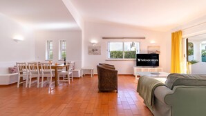 A spacious living room with a dining area, a sofa, and a TV. - Villa Uno by HelloVacations (Loulé)