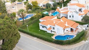 A residential area with houses featuring red-tiled roofs, a swimming pool, and well-maintained gardens. - Villa Uno by HelloVacations (Loulé)