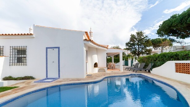 A swimming pool with a white building in the background. - Villa Uno by HelloVacations (Loulé)