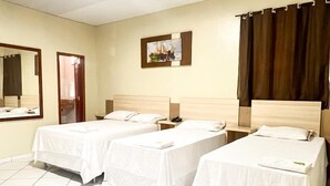 Una habitación de hotel con dos camas individuales, un espejo grande, un cuadro en la pared y una cortina en la ventana.