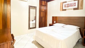 Un dormitorio con una cama grande, vigas de madera en el techo, un espejo y un cuadro en la pared.