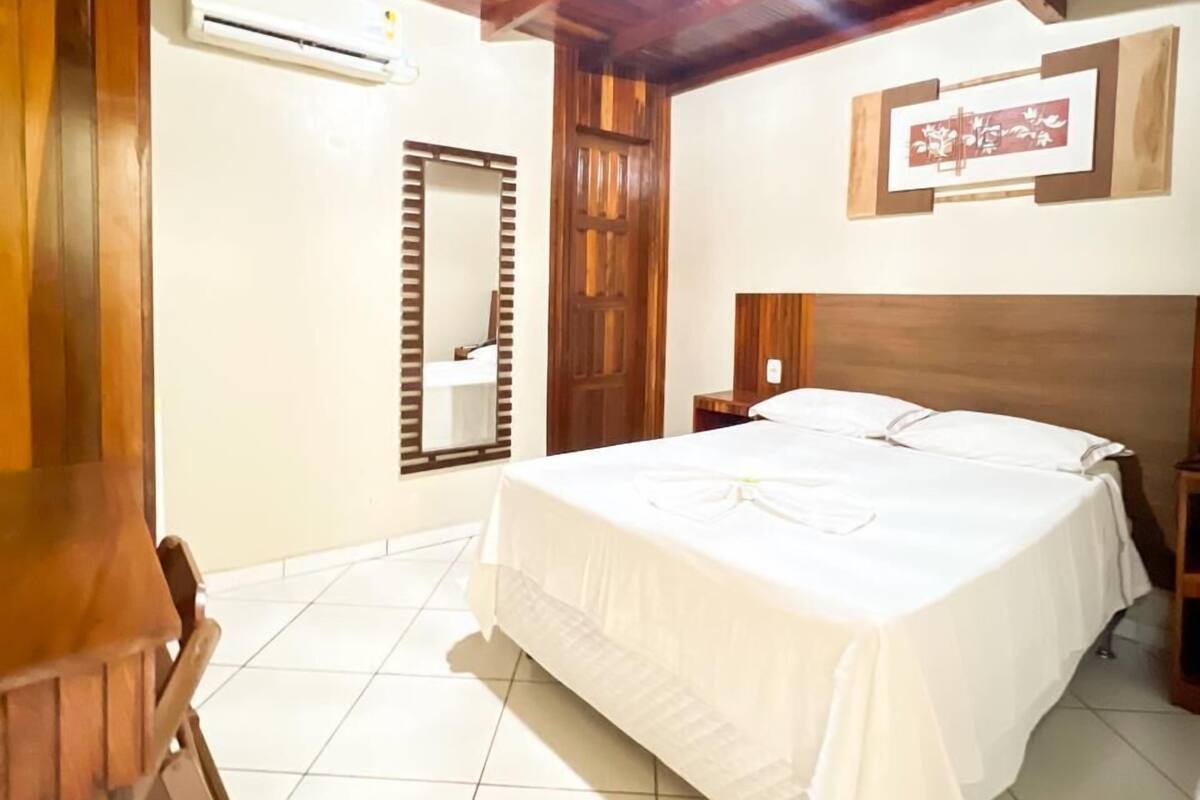 Un dormitorio con una cama grande, vigas de madera en el techo, un espejo y un cuadro en la pared.