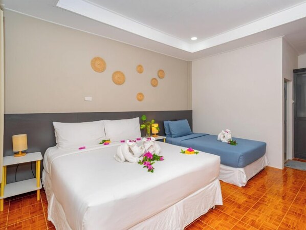 A hotel room with a large bed, a smaller bed, a bedside table with a lamp, and decorative wall art. - Lanta Beachfront Resort (Ko Lanta)