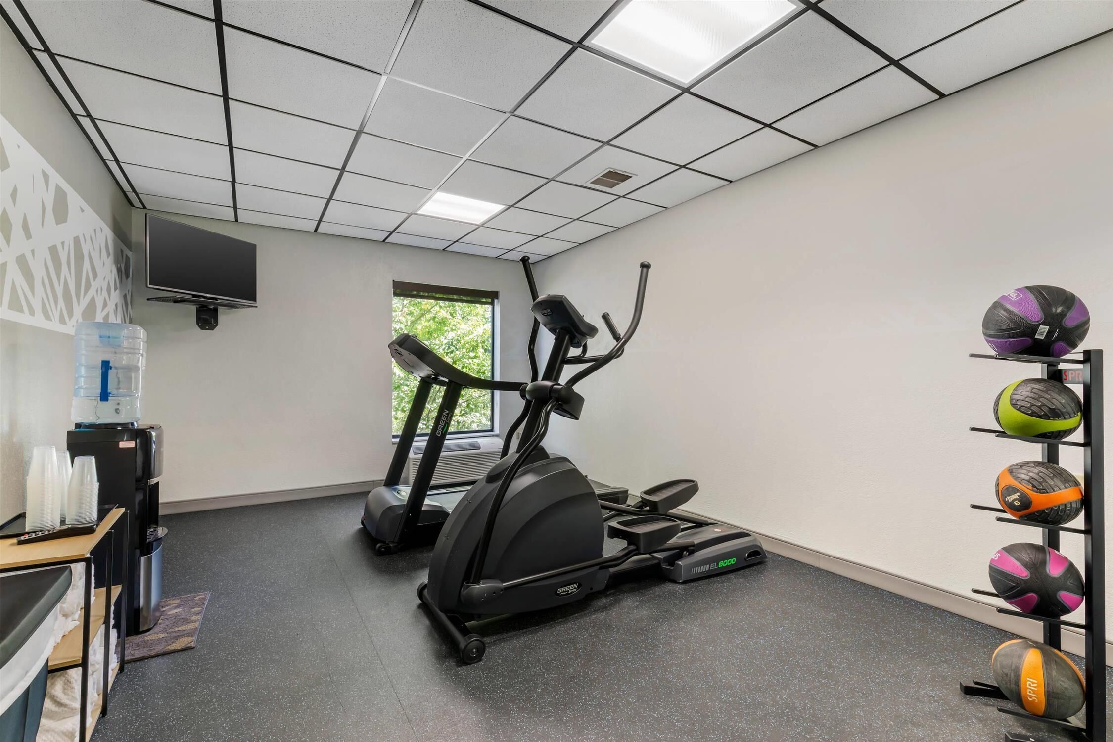 Une salle de sport équipée d’un appareil elliptique, d’un tapis de course et d’un distributeur d’eau.