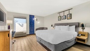 Une chambre d’hôtel moderne avec un grand lit, des tables de chevet, un bureau et une télévision.