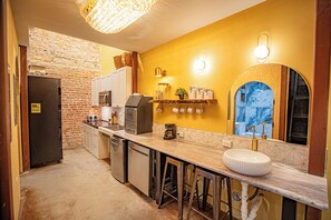 A compact kitchen with a brick wall, a refrigerator, a coffee maker, and a sink. - Social Stays On State Street (Santa Barbara)
