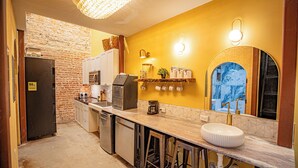 A compact kitchen with a brick wall, a refrigerator, a coffee maker, and a sink. - Social Stays On State Street (Santa Barbara)