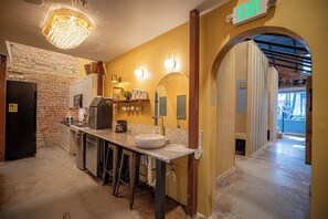 A kitchen with a brick wall, a sink, and a bar area. - Social Stays On State Street (Santa Barbara)