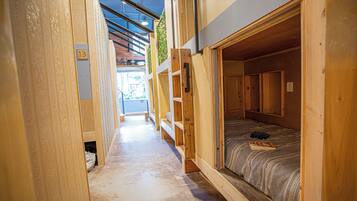 A narrow corridor with wooden bunk beds, each marked with a number.