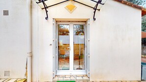 A building entrance with a glass door, a small porch area, and a green mat at the entrance.