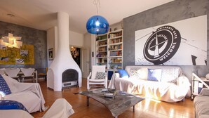 Uma sala de estar moderna com lareira, mobiliário branco, uma estante de livros e um grande letreiro de boas-vindas.