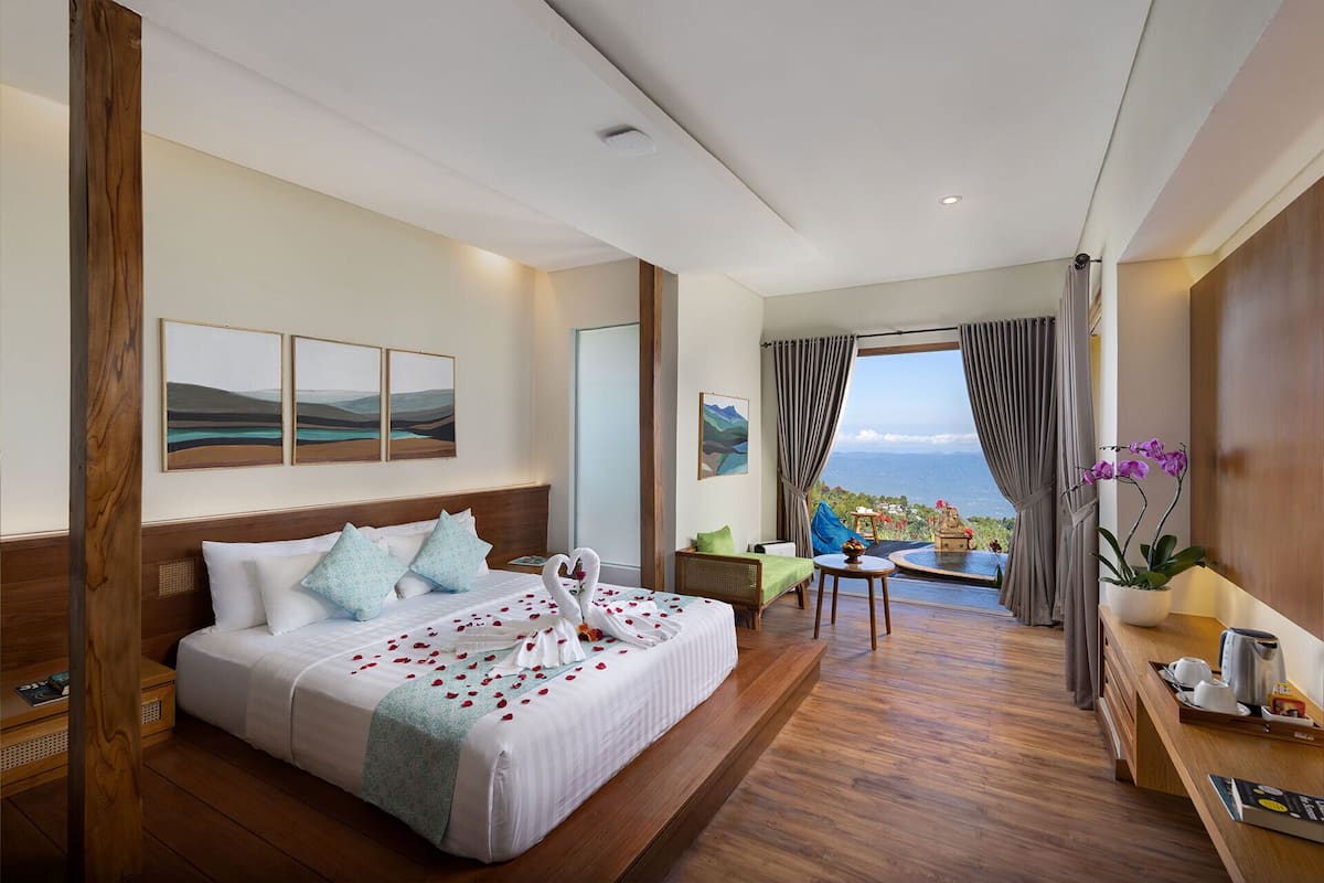 A hotel room with a large bed, a desk, a chair, and a view of the ocean.
