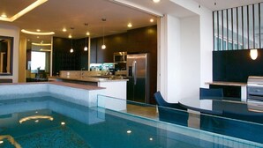 A modern kitchen with a built-in island, stainless steel appliances, and pendant lighting. - Signature by Pinnacle (Puerto Vallarta)