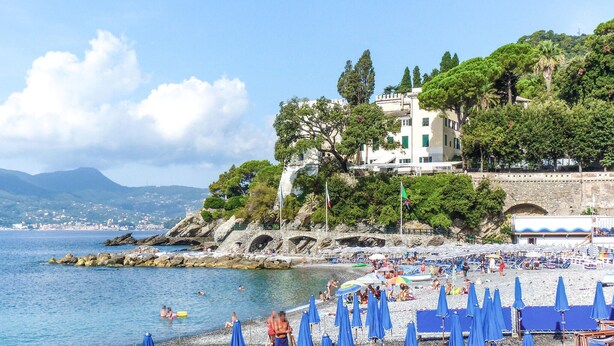 A coastal beach with a stone bridge, beach umbrellas, and a building with a balcony overlooking the sea. - 2 bedroom gorgeous apartment in Semorile (Semorile)