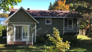 Une maison à deux étages avec un porche à l’avant, une petite terrasse et un garage.