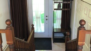 Un escalier avec des balustrades en bois et un paillasson noir à sa base.