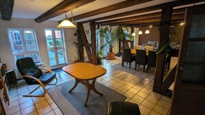 Een eethoek met een houten tafel en stoelen, een hanglamp en uitzicht op het landschap door grote ramen.