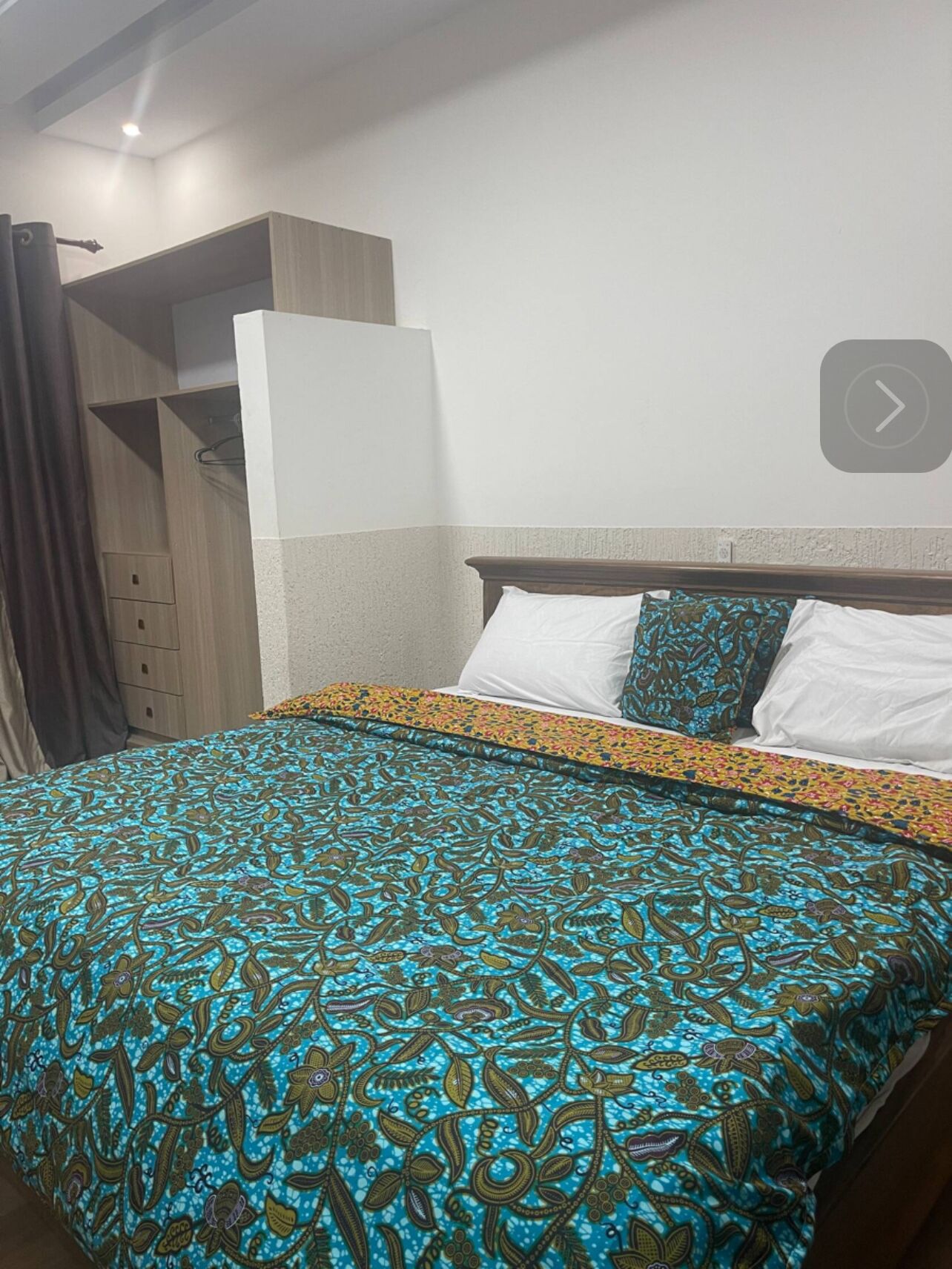 A hotel room with a bed, a wardrobe, and a small closet.