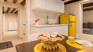 A modern kitchen with white cabinets, a yellow refrigerator, and a decorative bowl on the table. - Ramo delle Moschette (Venezia)