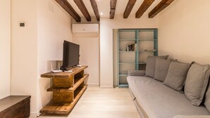 A modern living room with a wooden entertainment unit, a grey sofa, and a teal shelving unit. - Ramo delle Moschette (Venezia)