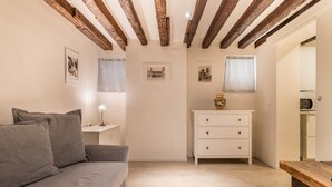 A room with a grey sofa, a white dresser, and a wooden bench. - Ramo delle Moschette (Venezia)