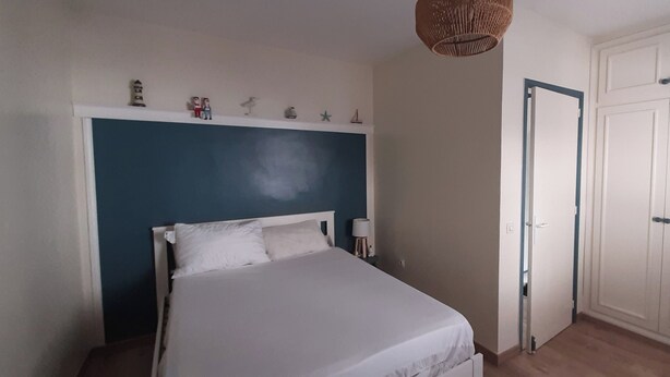 Ein Schlafzimmer mit einem Bett, einem Nachttisch, einem Kleiderschrank und einem an der Wand befestigten Regal mit Dekoration.