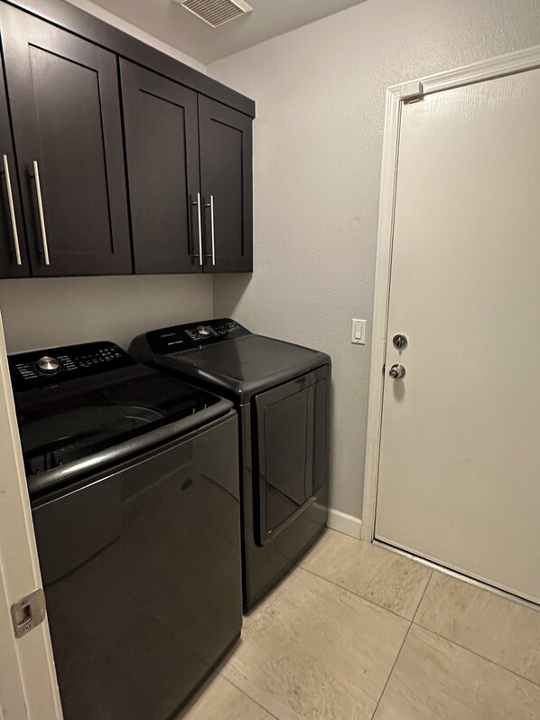 A laundry room with a washer and dryer, a door, and cabinets.