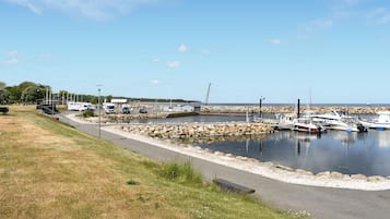 En småbåtshamn med förtöjda båtar, en parkeringsplats och ett grönområde med en gångstig.
