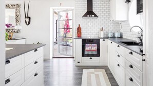 A modern kitchen with white cabinetry, a black range hood, and a large window. - 3 bedroom cozy home in Tomelilla (Tomelilla)