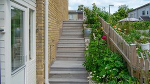 A residential staircase leading to a wooden deck with a garden.