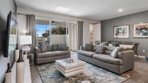 Ein modernes Wohnzimmer mit zwei grauen Sofas, einem Couchtisch und einem Fernseher an der Wand.