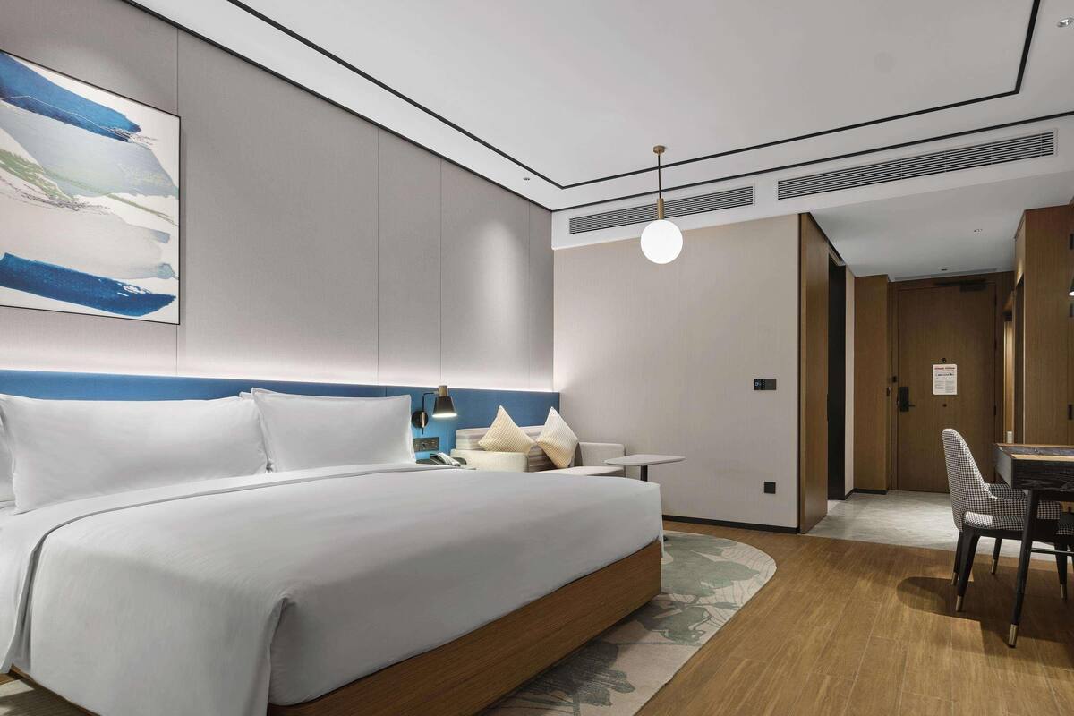 Une chambre d’hôtel moderne, dotée d’un grand lit, de tables de chevet, d’un bureau et d’une chaise.