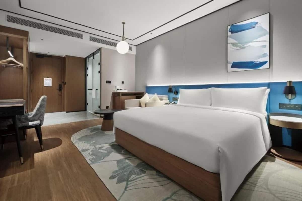 A modern hotel room with a large bed, a desk, and a chair.