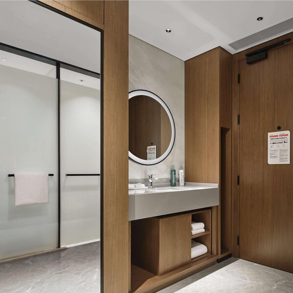 A modern bathroom with a wooden vanity, a large mirror, and a glass shower enclosure. - Hilton Garden Inn Beijing Yizhuang (Beijing)