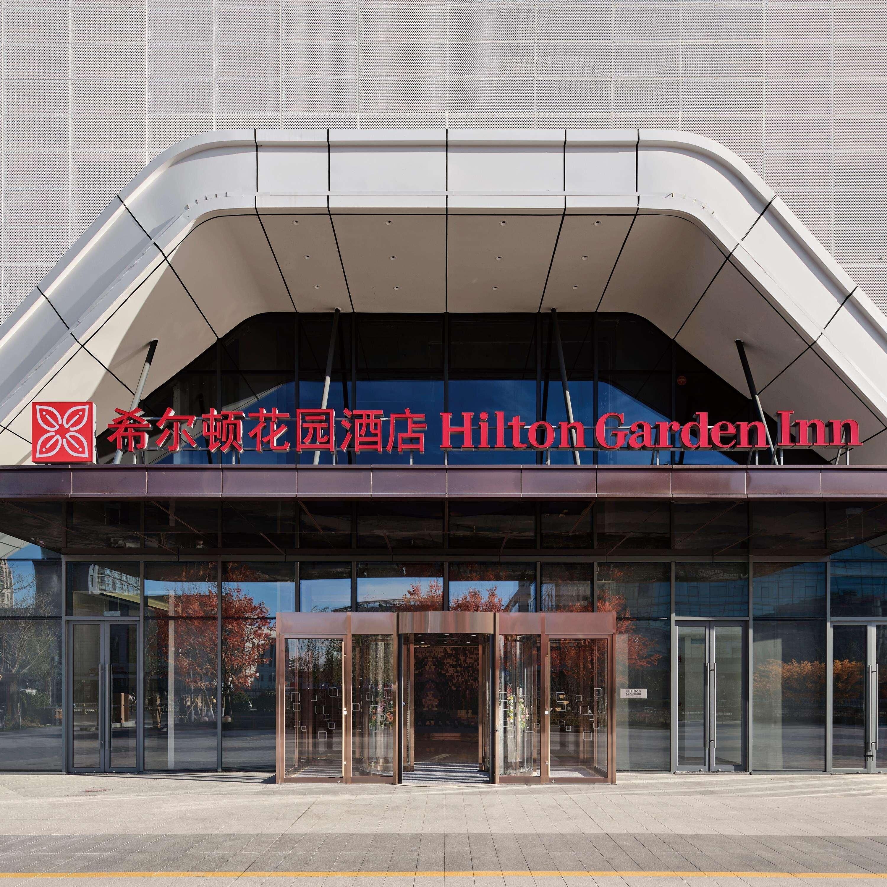 El exterior del Hilton Garden Inn, con un diseño moderno, presenta un techo curvo y amplias puertas de entrada de vidrio.