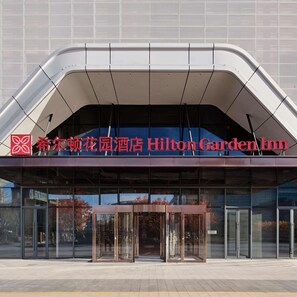 The exterior of the Hilton Garden Inn with a modern design, featuring a curved roof and large glass entrance doors. - Hilton Garden Inn Beijing Yizhuang (Beijing)