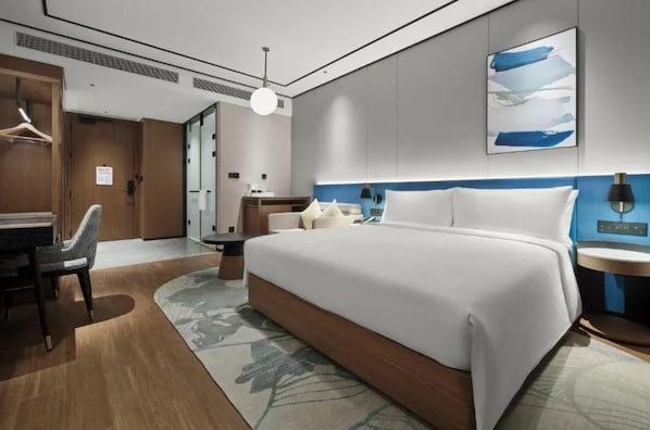 Una habitación de hotel moderna con una cama grande, un escritorio y una silla.