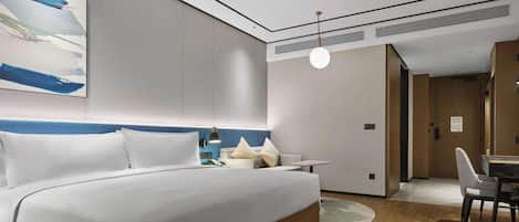 Une chambre d’hôtel moderne, dotée d’un grand lit, de tables de chevet, d’un bureau et d’une chaise.