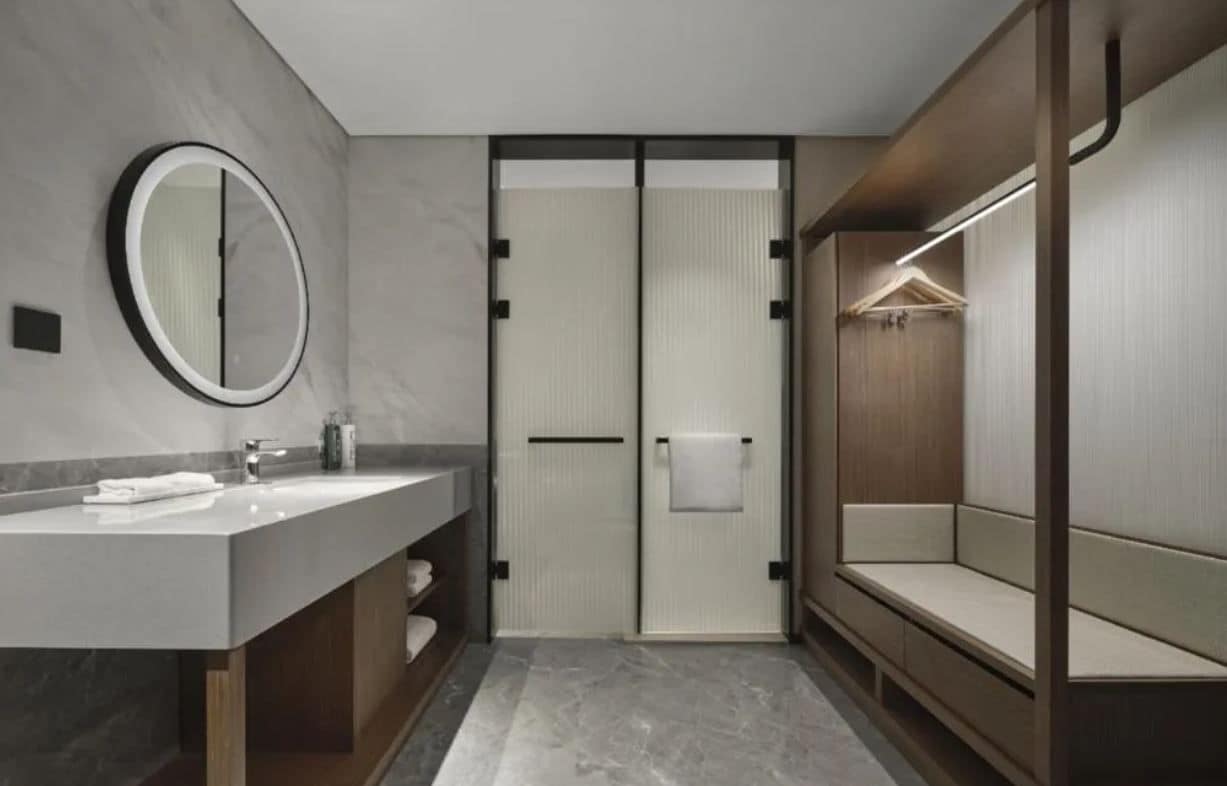 Ein modernes Badezimmer mit einem großen Spiegel, einem Waschtisch und einer begehbaren Dusche.