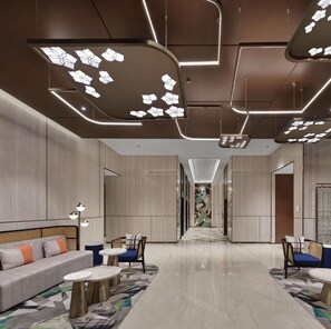 A modern hotel lobby with a central seating area, a patterned wall, and a long corridor leading to other rooms. - Hilton Garden Inn Beijing Yizhuang (Beijing)