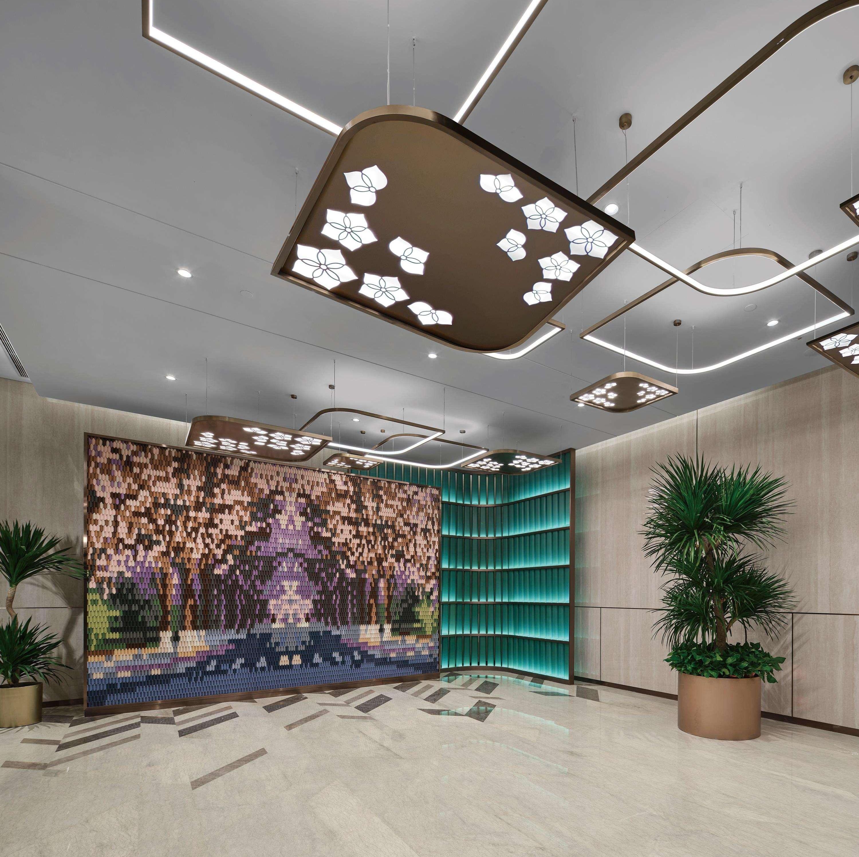 Eine moderne Lobby mit Wandverkleidung mit Muster, eingelassener Beleuchtung und einer gewölbten Akzentwand in Türkis.
