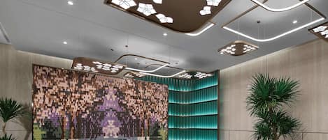 A modern lobby with a patterned wall, recessed lighting, and a curved teal accent wall.