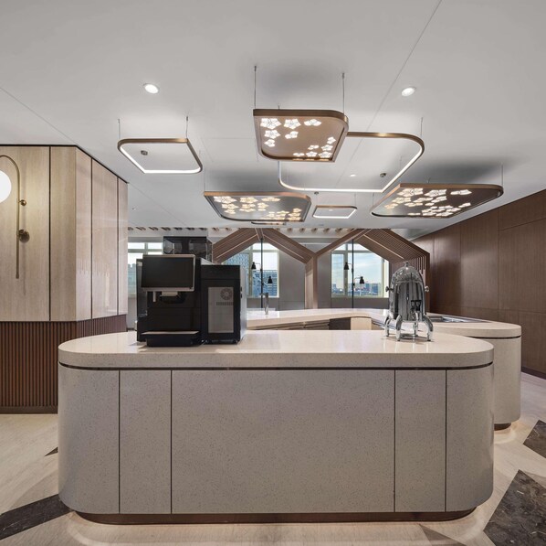 A modern reception area with a curved counter, a coffee machine, and a water dispenser. - Hilton Garden Inn Beijing Yizhuang (Beijing)