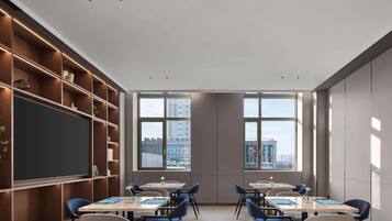A conference room with a large blackboard, wooden shelving, and multiple tables with chairs.