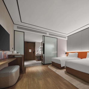 A modern hotel room with a wooden desk, a bed with white bedding, a large mirror, and a separate bathroom area.